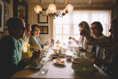 a group of people gather around a meal of fish and stew in the faroe islands