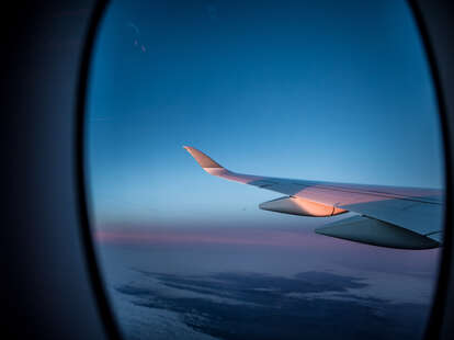 The view from the window seat of an airplane flying at sunset. 