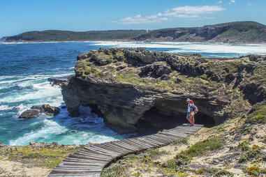 two people walking along a seaside trail on plettenberg bay