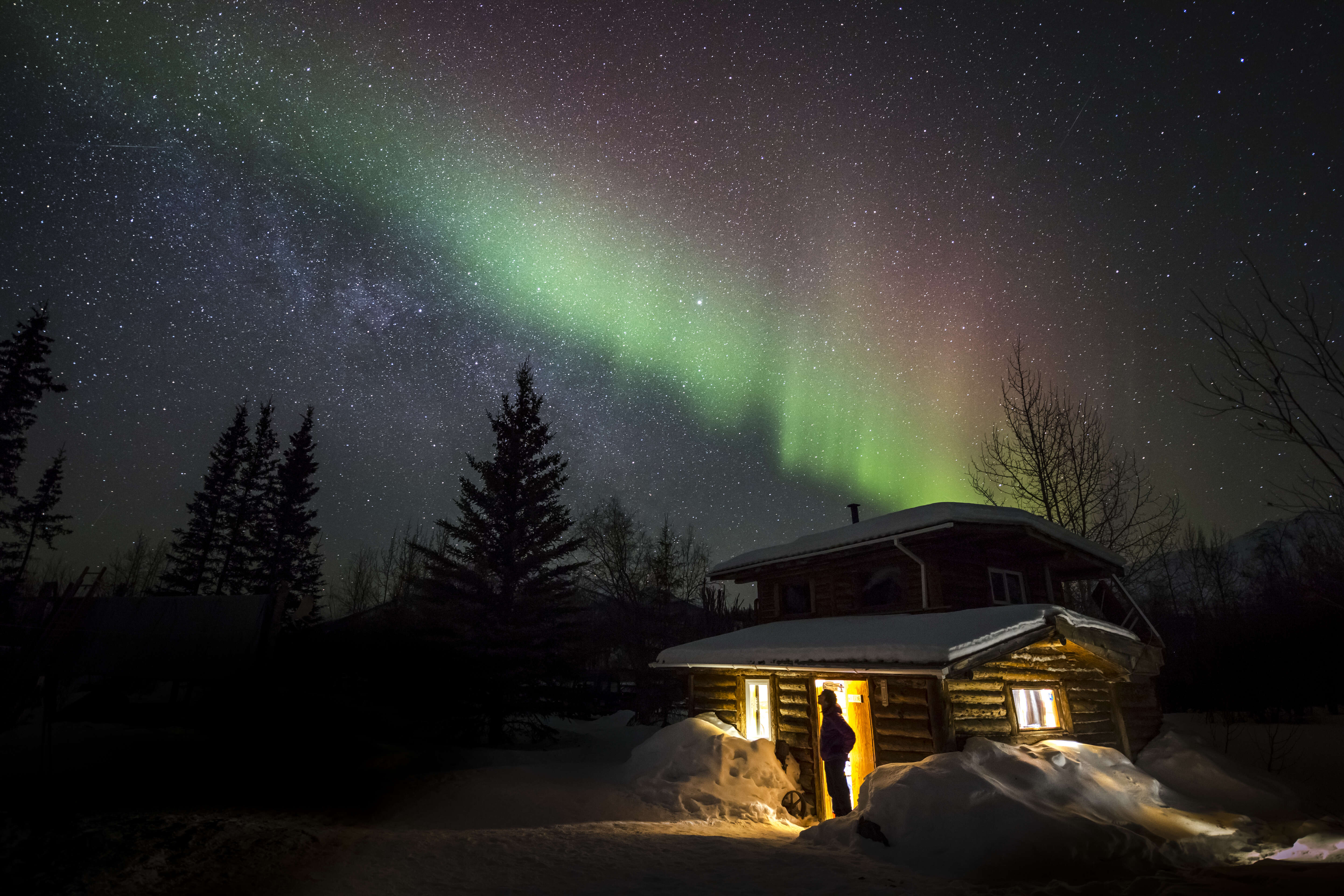 cabin beneath northern lights in alaska