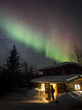 cabin beneath northern lights in alaska