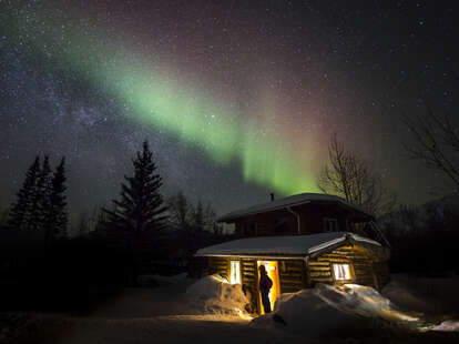 cabin beneath northern lights in alaska