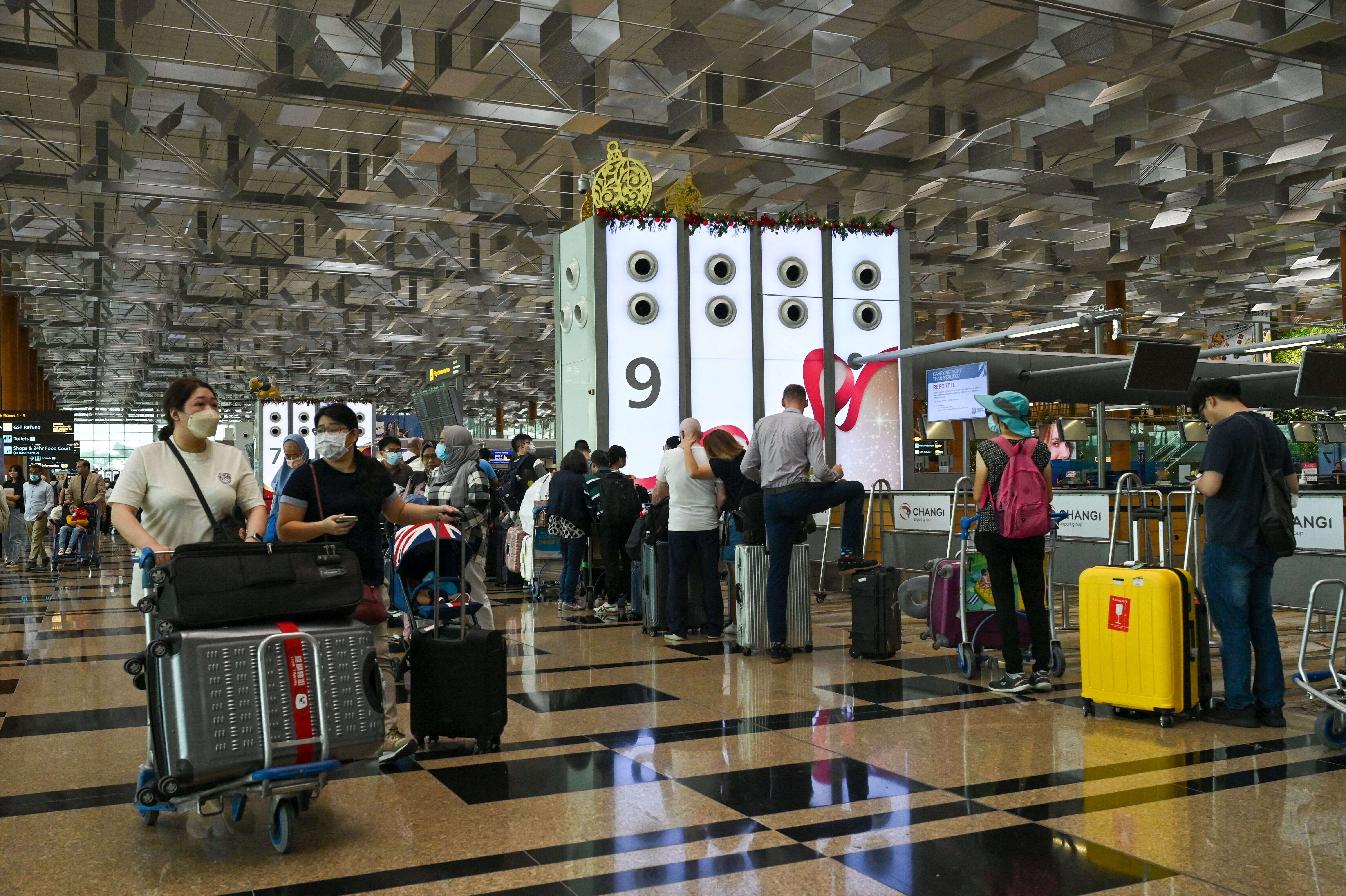 Travellers queue to check-in for their flight departure at Singapore Changi airport