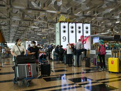 Travellers queue to check-in for their flight departure at Singapore Changi airport