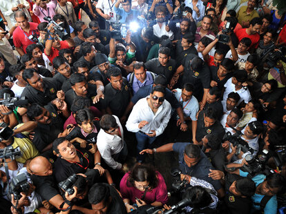 bollywood actor surrounded by adorning fans as they all look up to a camera overhead