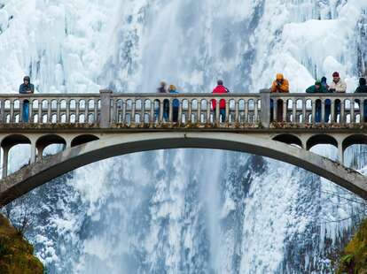 tourists visiting bridge at multnomah falls in winter