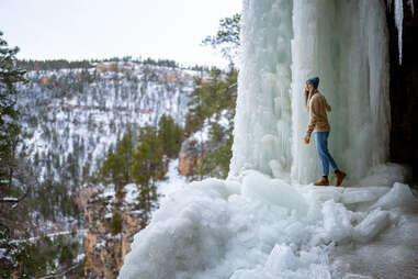 woman standing amongst frozen waterfall at spearfish canyon