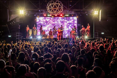 la bomba del tiempo performs under a giant light and in front of a large crowd