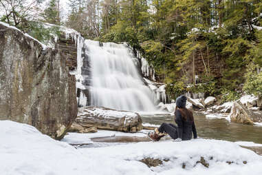 woman sitting near muddy creek falls in swallow falls state park 