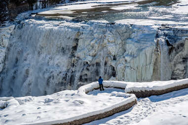 hiker in front of waterfalls in letchworth state park during winter