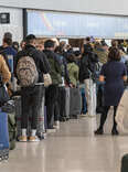 Travelers wait to check in at the American Airlines ticket counter at San Francisco International Airport