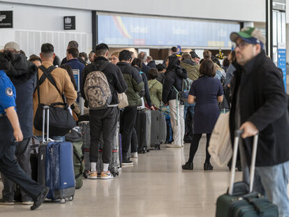 Travelers wait to check in at the American Airlines ticket counter at San Francisco International Airport