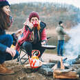 group of campers preparing food around a campfire in winter