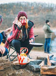 group of campers preparing food around a campfire in winter