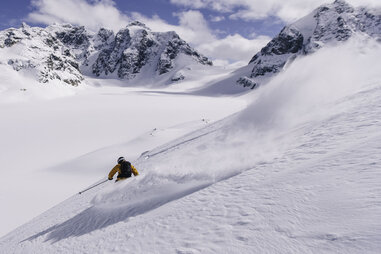 skiier headed down the powdery slopes in the chugach mountain range in alaska