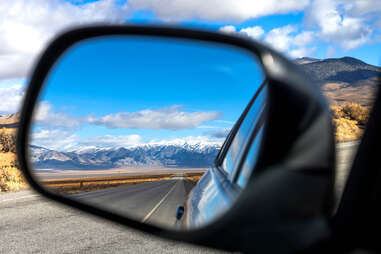 mountains in the rearview mirror of a car as the driver heads down us highway 50 in nevada