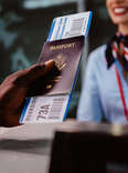 Man holding boarding pass and passport at airline check-in desk at international airport.