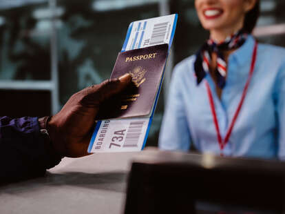 Man holding boarding pass and passport at airline check-in desk at international airport.