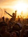 General view of the huge crowds enjoying the music at a music festival during a sunny day. 