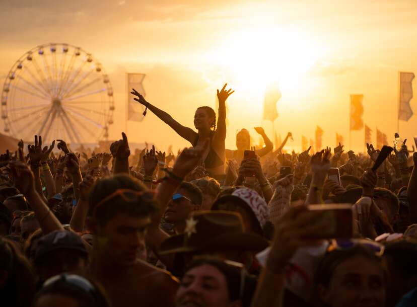 General view of the huge crowds enjoying the music at a music festival during a sunny day. 