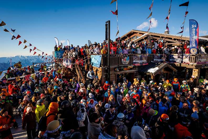 people in snow gear outdoors around a wooden chalet