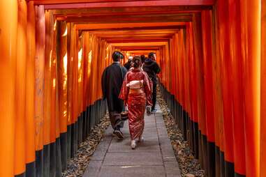 people passing under fushimi inari temple