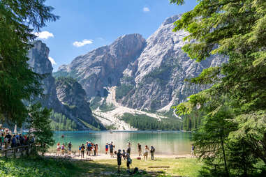 tourists enjoying lake braies in prags, reflecting surrounding mountains 