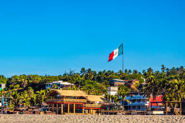colorful beach shacks on zicatela beach with mexican flag