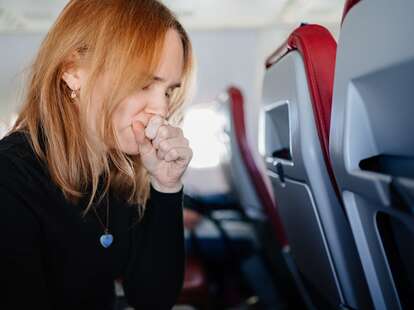 woman coughs up a sore throat flying on an airplane.