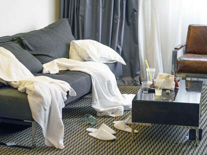 Messy hotel room with scattered bathrobes and plastic cups