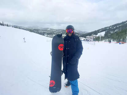woman, standing, on a mountain, holding a snowboard