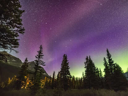auroral arc across a purple and green sky in banff national park at night