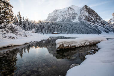 lake louise with stones at the bottom surrounded by snow and foregrounding a mountain at banff