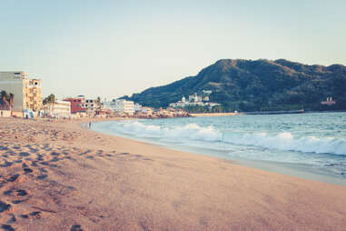 Small town beach in Mexico at sunset with mountain in background in Barra de Navidad, Jalisco, Mexico