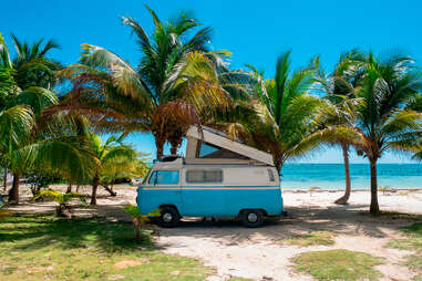 Van on a beach near palm trees, Mahahual village, coast of Quintana Roo state in Mexico 