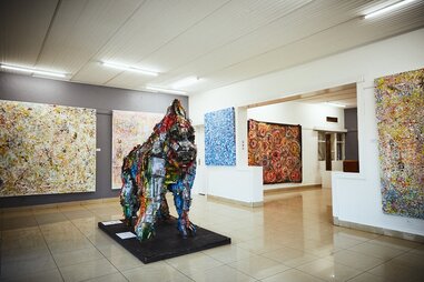a gorilla sculpture surrounded by walls of paintings in the inema arts center in kigali, rwanda