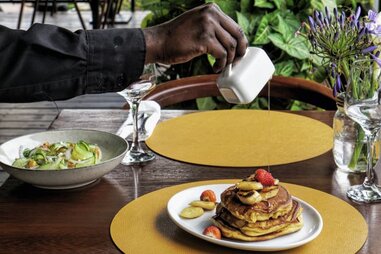 man pouring syrup over pancakes at poivre noir in kigali