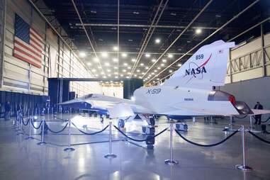 the x-59 aircraft with nasa logo roped off in a giant hangar