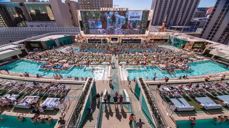 pools with people in front of a large screen showing sports