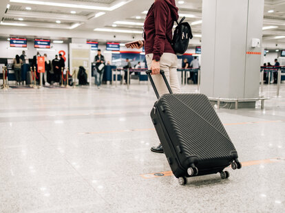 Woman standing with suitcase in modern airport terminal