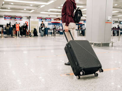 Woman standing with suitcase in modern airport terminal 
