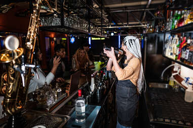 Bartender young woman preparing tiki drink behind a bar