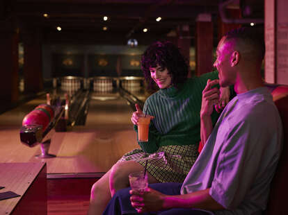Happy couple having drink at bowling alley
