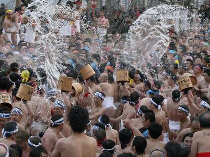 loincloth-clad men tossing buckets of water on each other