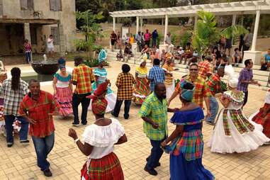 islanders in st. croix dancing at a public square wearing colorful clothes