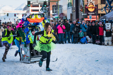 ladies in costume pulling another lady on a outhouse sled