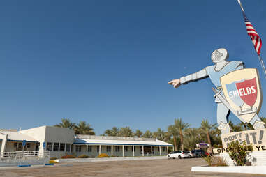 a giant roadside knight pointing at a shed