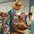 archival photo of flight attendant serving a ginger ale to an airplane passenger who is smiling