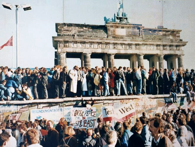 germans stand around and on top of the berlin wall before the fall