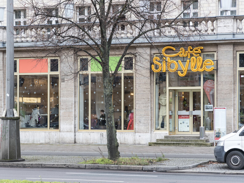 storefront of cafe sibylle which is known for its yellow neon sign